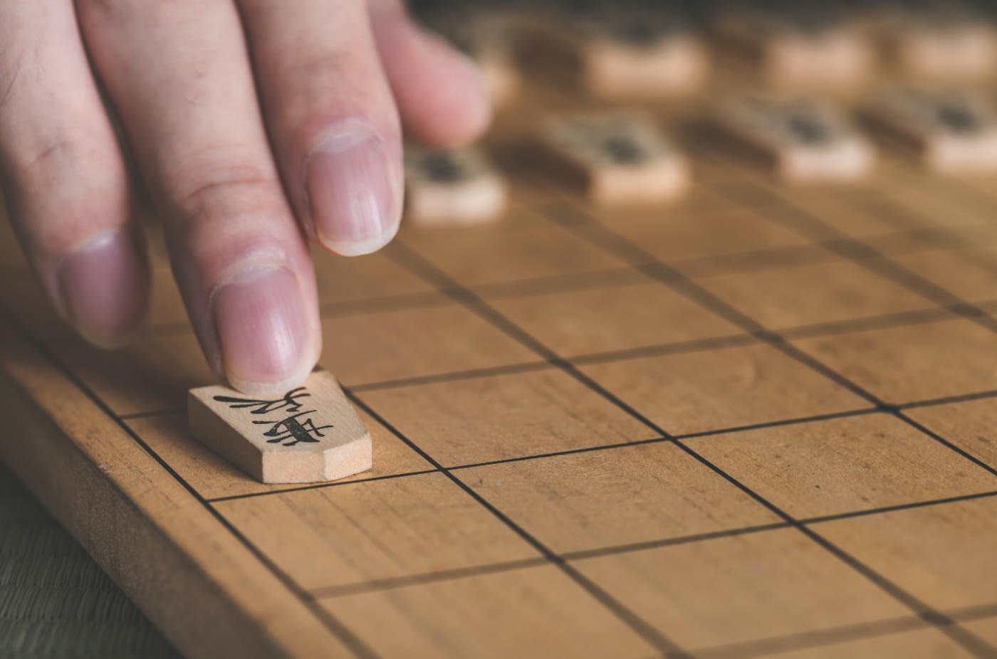 将棋盤の端の駒に指をそえる手